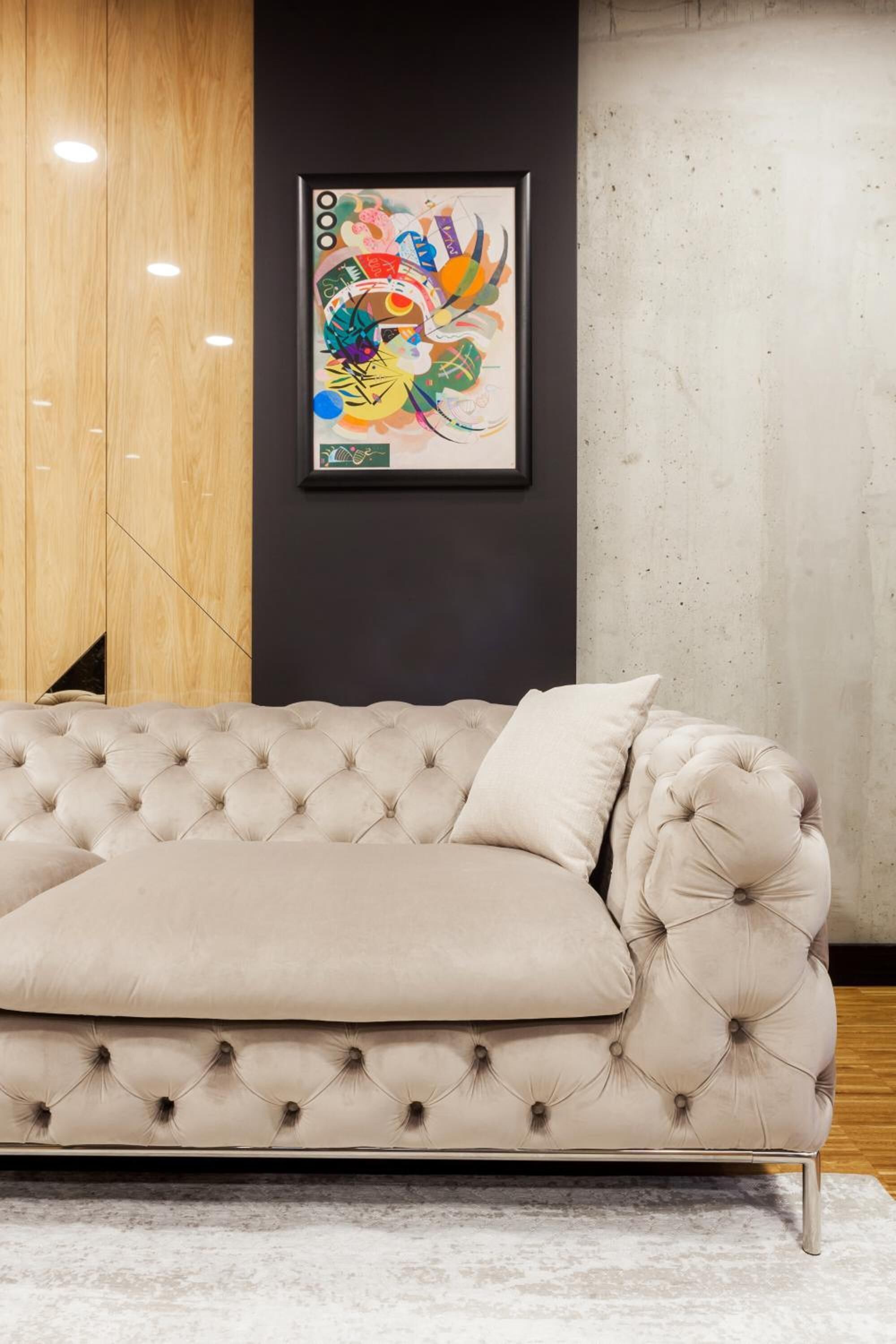A beige tufted sofa with a cushion, positioned on a light-colored rug.