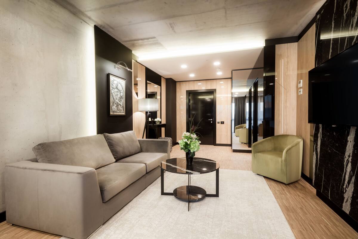 A modern living room with a sofa, a glass coffee table, and a green armchair.
