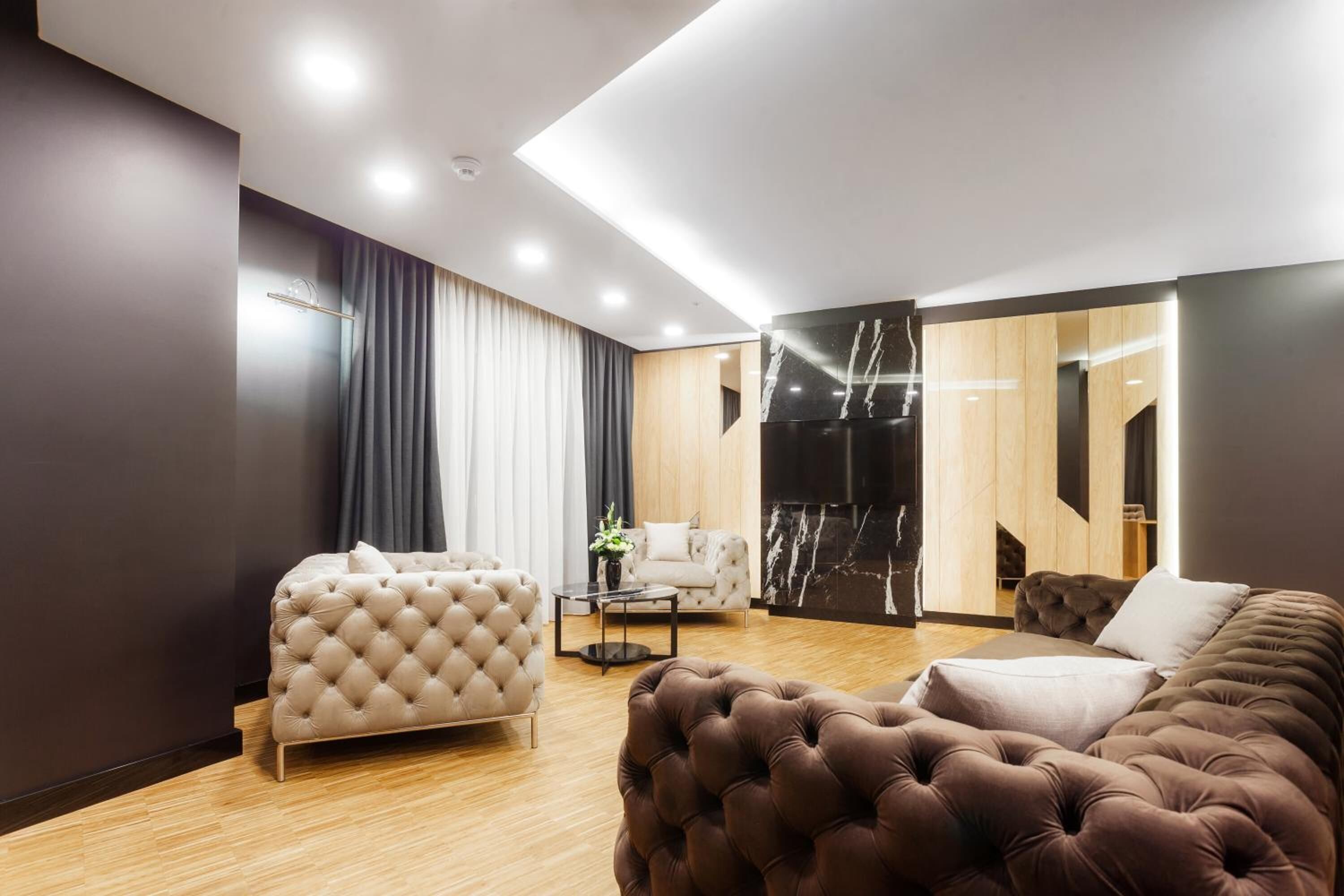 A modern living room with a tufted sofa, a white armchair, and a coffee table.