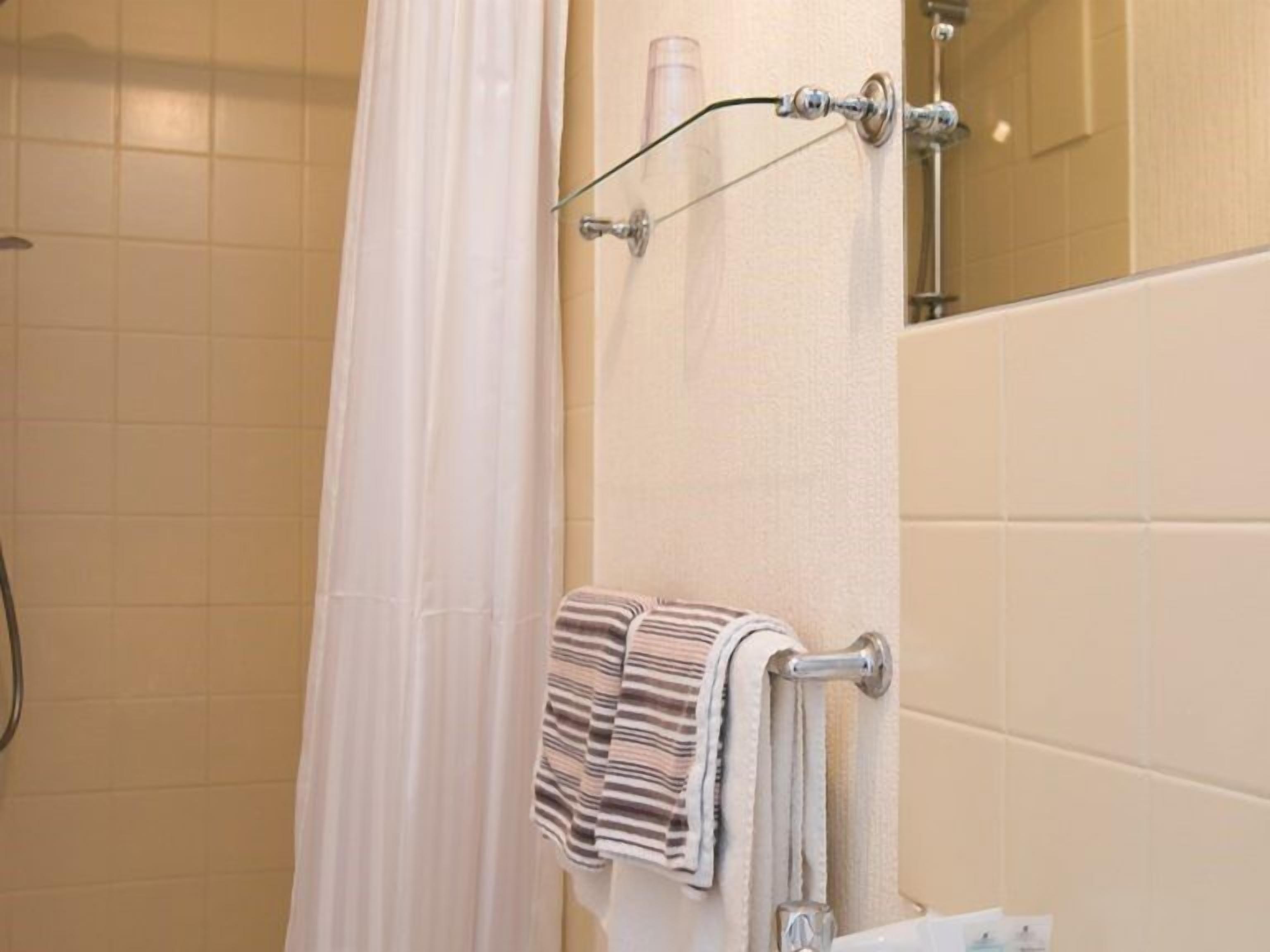 A bathroom with a shower curtain, a towel rack with a striped towel, and a toilet.