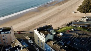 Complejo de edificios costeros con varias unidades residenciales, un estacionamiento y una playa al fondo.