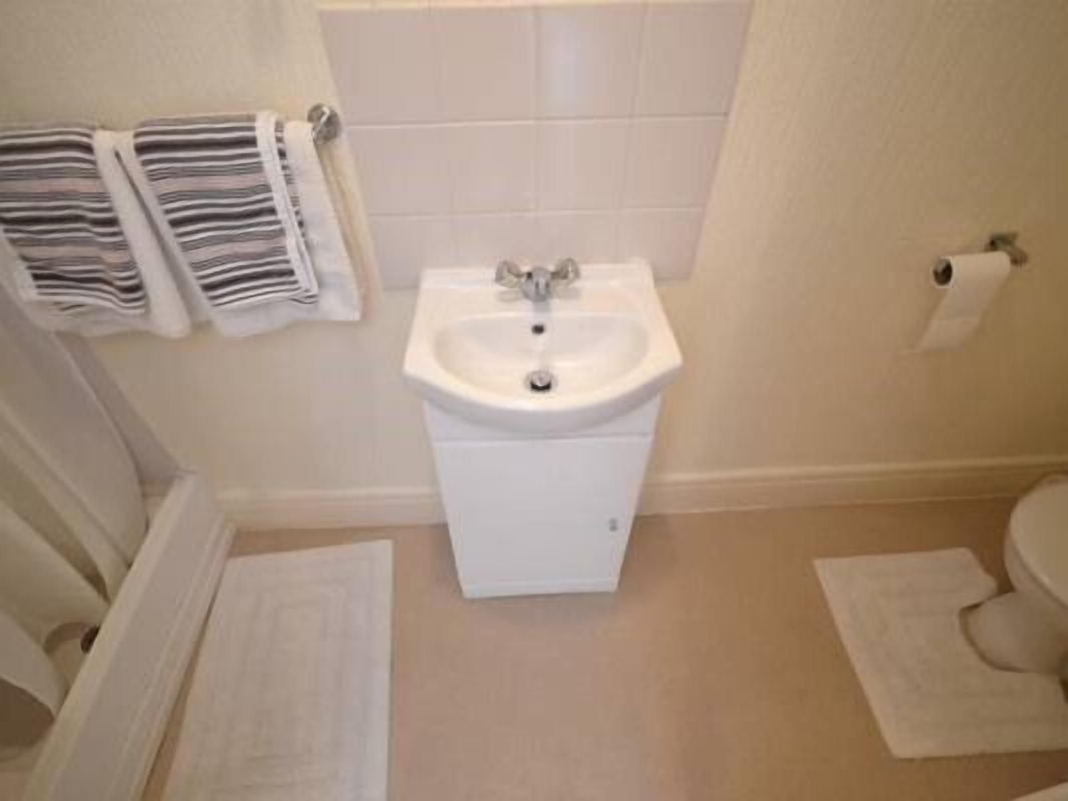 Een badkamer met een wit wastafel, een toilet en twee witte handdoeken op de vloer.