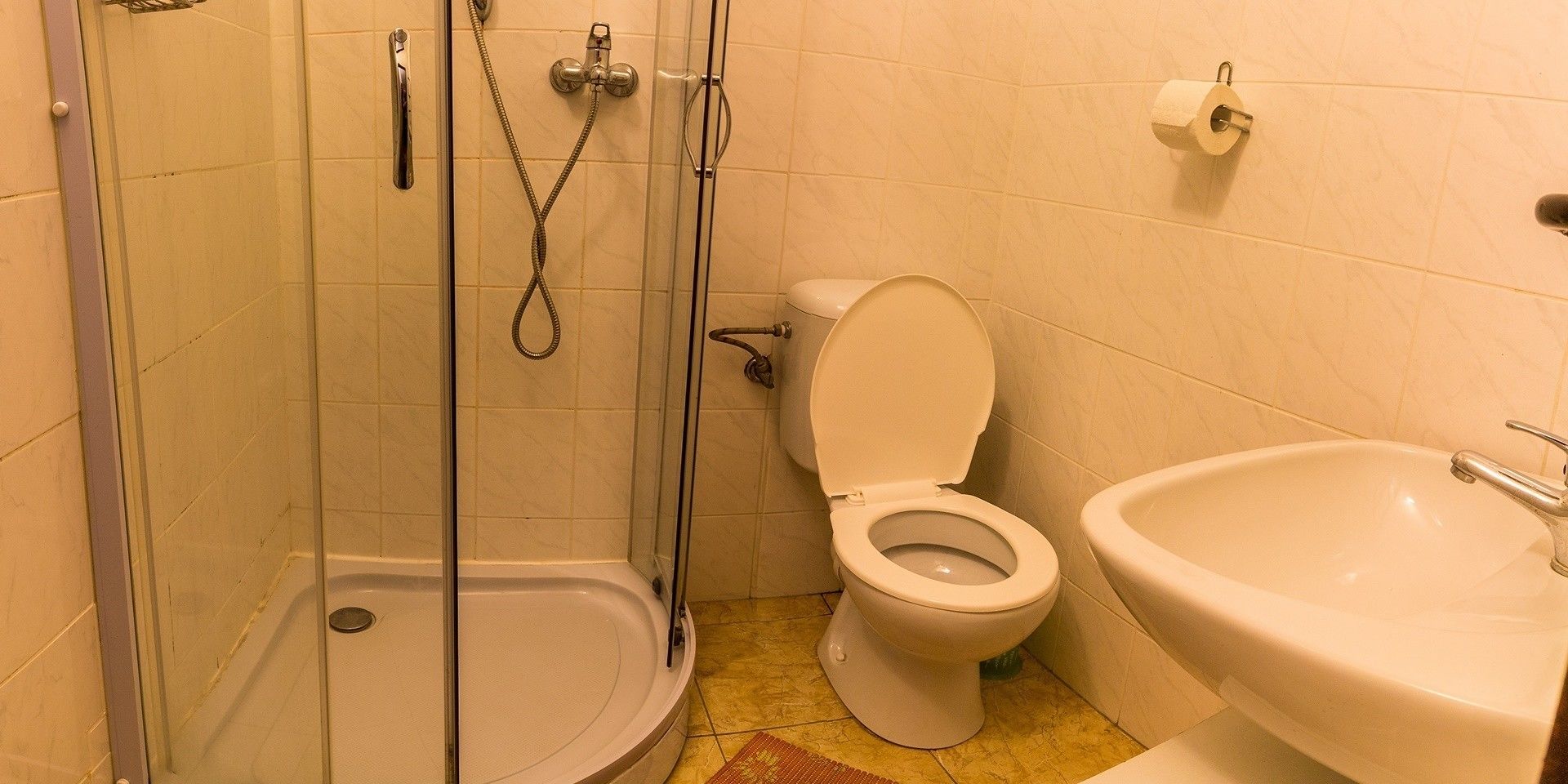 A bathroom with a glass-enclosed shower, a toilet, and a sink.