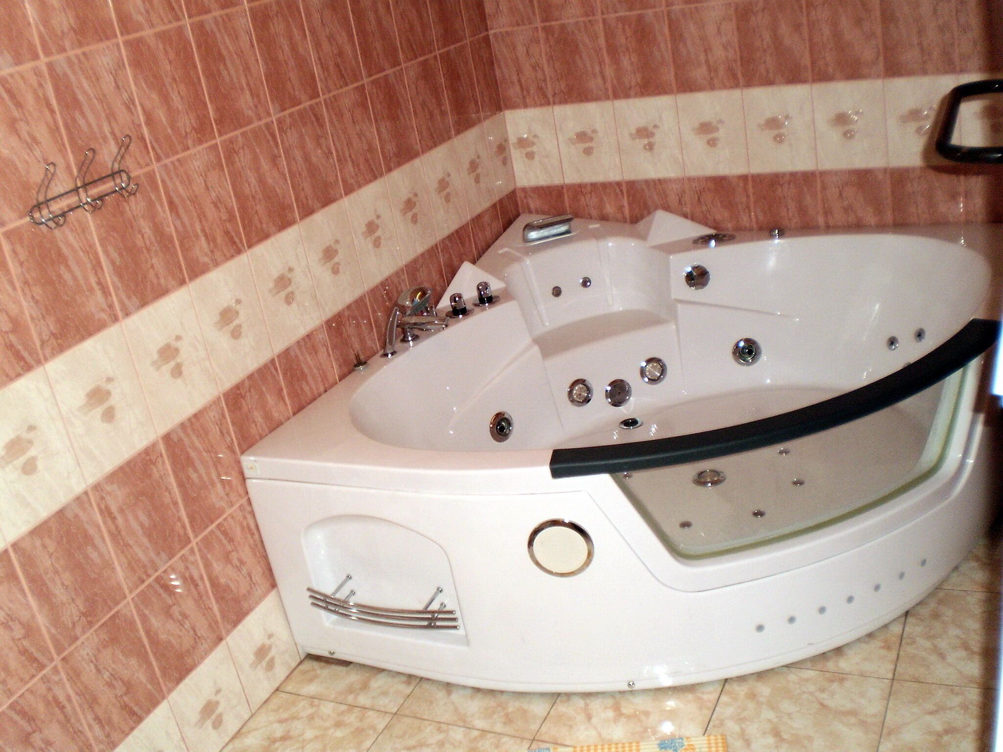 Baño con una bañera blanca, ducha e inodoro. Las paredes están revestidas con un diseño.