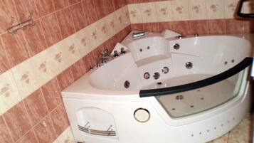 Baño con una bañera blanca, ducha e inodoro. Las paredes están revestidas con un diseño.