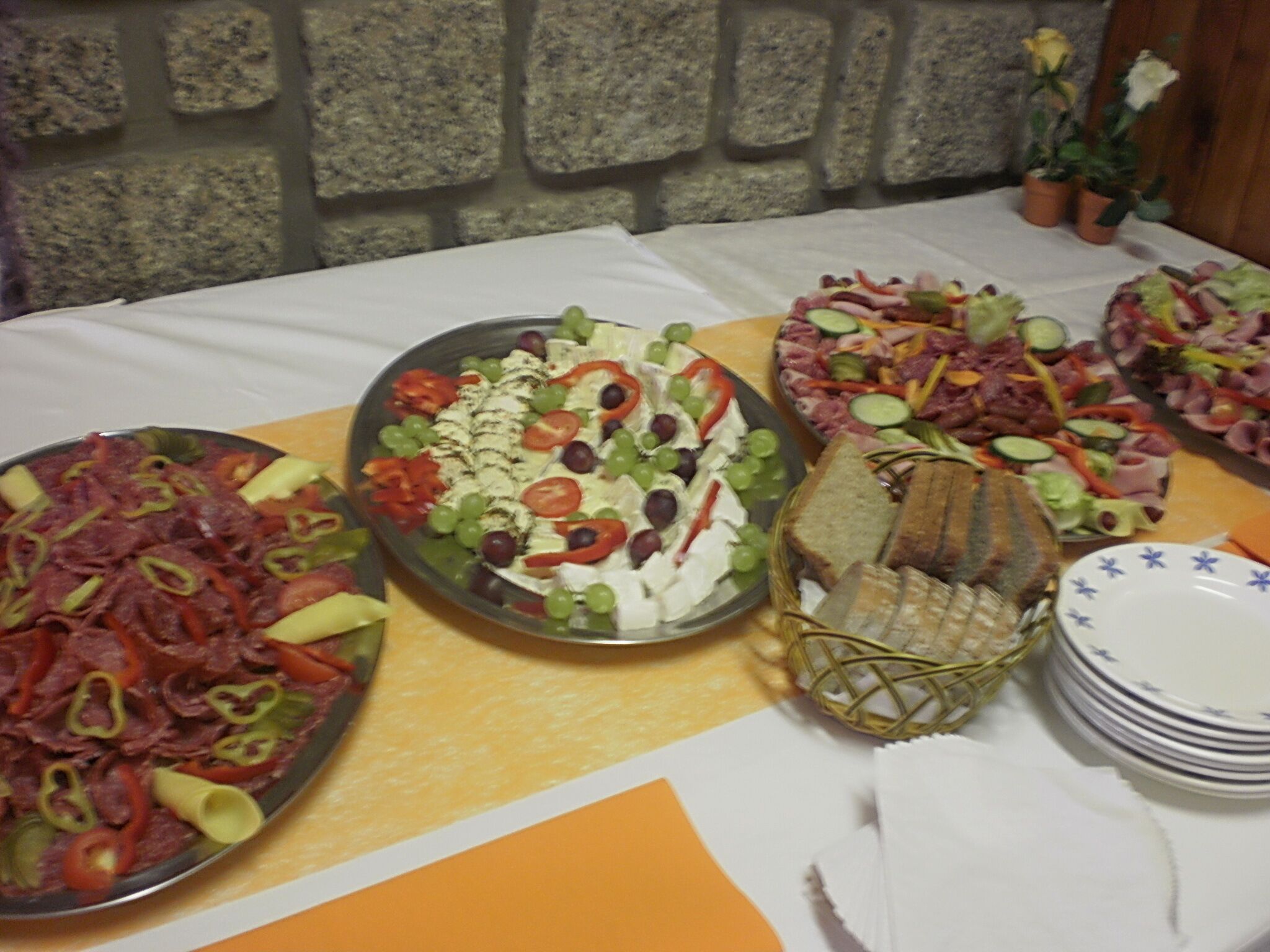 Una mesa con diferentes bandejas de comida, que incluyen una ensalada, un plato de carne y una bandeja de queso y verduras.