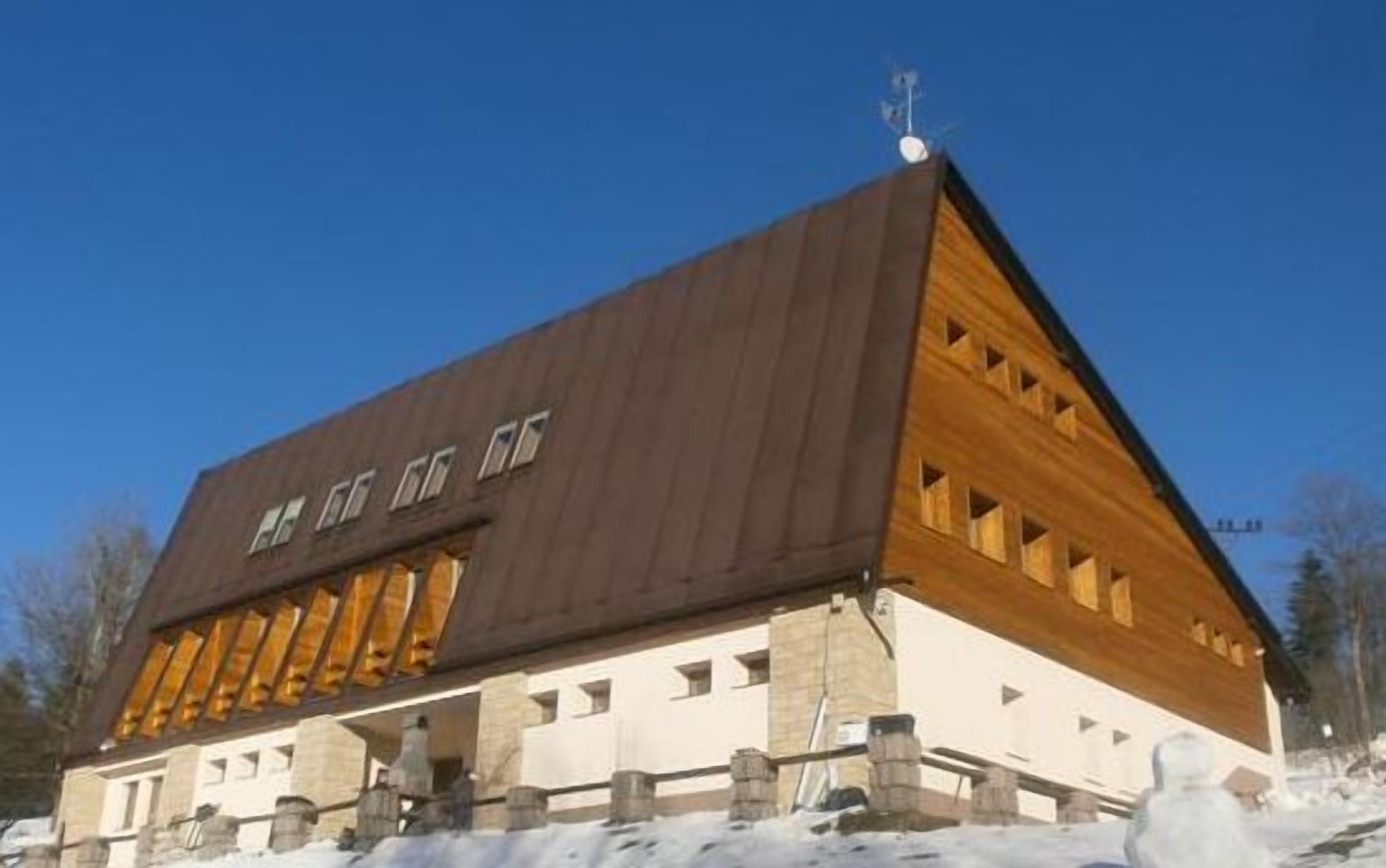 A large, modern building with a prominent sloped roof and multiple windows.