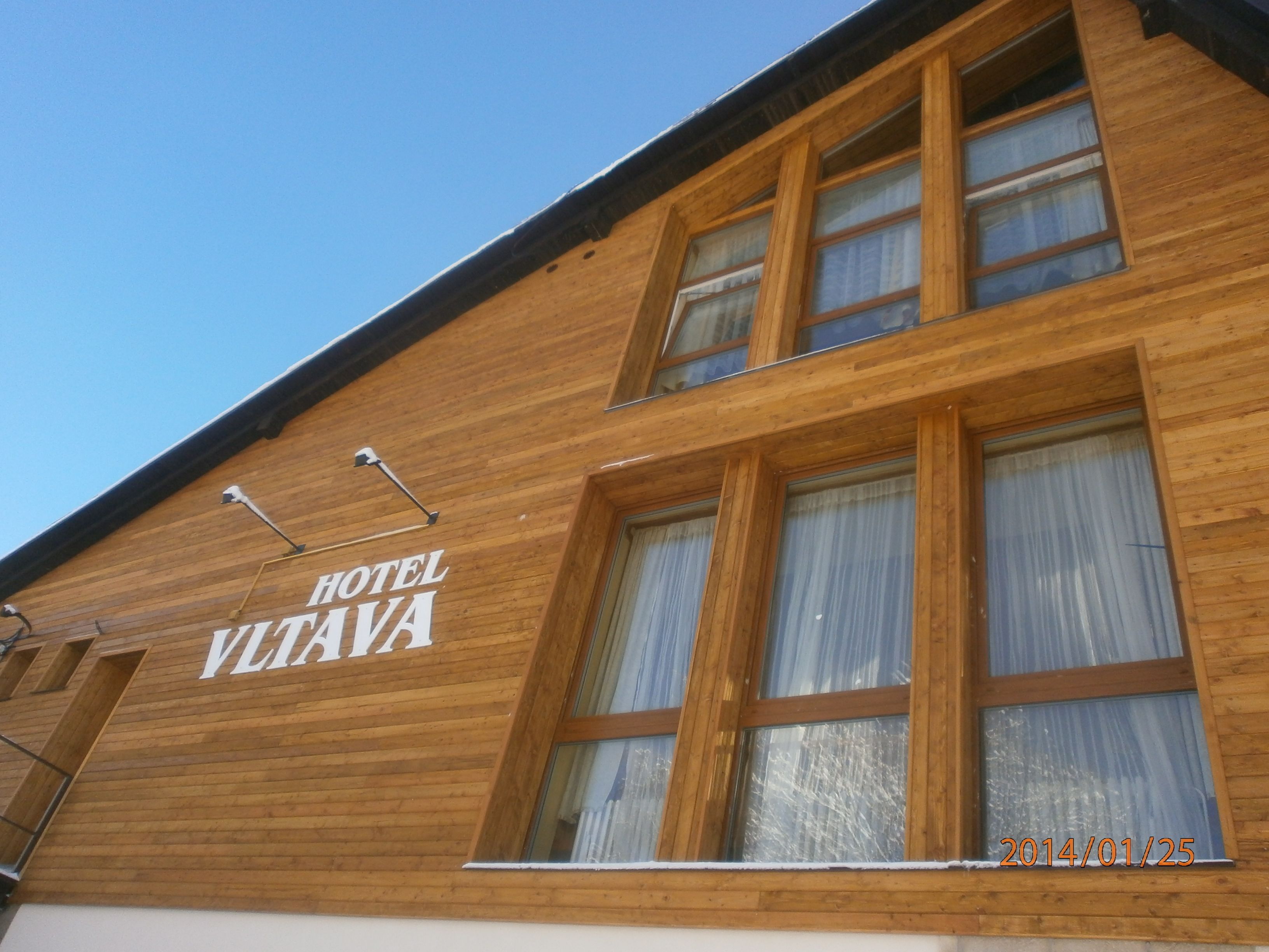 A wooden building with the sign "HOTEL VLTAVA" on the side.