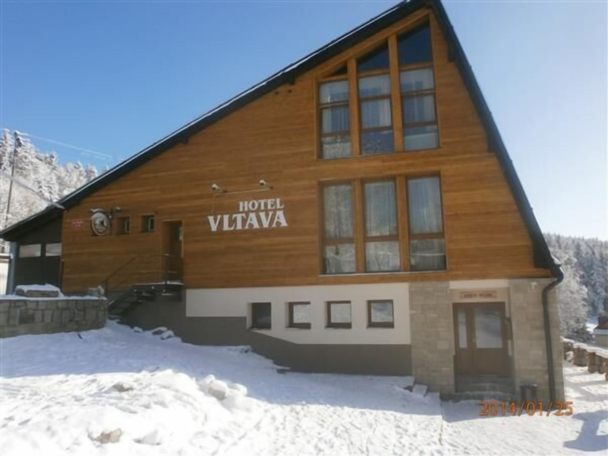 Un bâtiment en bois sur lequel on peut lire l’inscription « HÔTEL VLTAVA ».