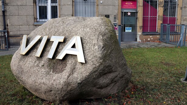 A large stone with the letters "VITA" carved into it, placed on grass in front of a building with a sign that reads "VITA." - Hotel Vita Berlin (Berlin)