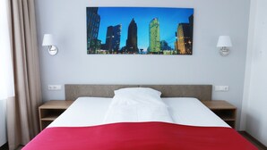 A hotel room with a bed, a cityscape painting on the wall, and two bedside lamps. - Hotel Vita Berlin (Berlin)