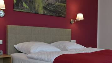 Une chambre d’hôtel avec un lit, deux lampes fixées au mur et un tableau accroché au mur.