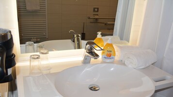 Un bagno con un lavandino bianco, uno specchio, un asciugamano e una bottiglia di crema Pure Basic.