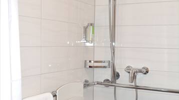 Eine moderne Dusche mit chromfarbenen Armaturen, einer in Glas eingefassten Duschbrause und einem Handbrausehalter.
