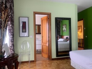 A room with a bed, a mirror, a door leading to a bathroom, and a green wall.