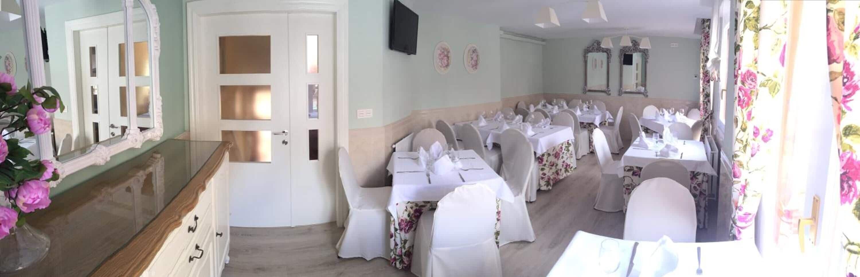 A dining area with tables set for a meal, a staircase leading to another floor, and a door with frosted glass panels.
