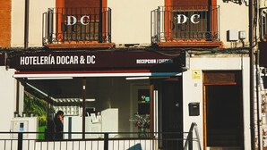 A building with balconies, a reception area, and a sign reading "HOTELERÍA DOCAR & DC". - Hostal Docar (Lerma)