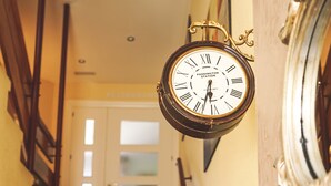 A staircase with a hanging clock and a mirror on the wall. - Hostal Docar (Lerma)