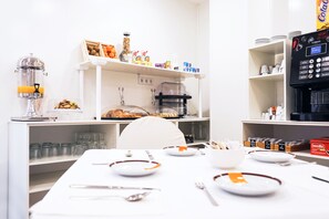 Un buffet de petit-déjeuner comprenant une machine à café, une présentation de fruits et divers aliments disposés sur des étagères.