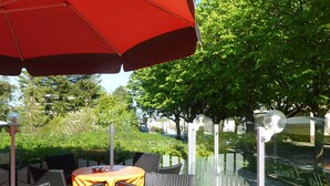 Outdoor seating with tables and chairs, a red umbrella, and a white picket fence. - Strandhotel Villa Louisa & Appartementhäuser Villa Josephine und Christine (Breege)