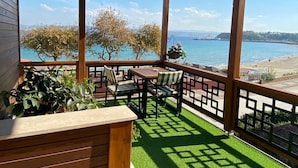 A covered outdoor seating area with a view of the sea and a beach. - Tas Konak Boutique Hotel (Gallipoli)