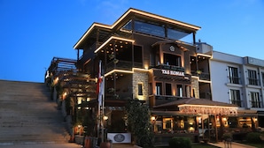 A multi-story building with a sign reading "TAS KONAK HOTEL" and a cafe area with outdoor seating. - Tas Konak Boutique Hotel (Gallipoli)