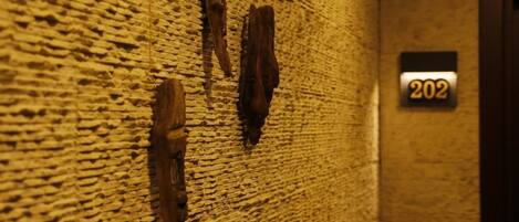 A textured wall with three wooden carvings and a door with the number 202.