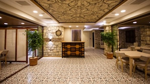 A hotel lobby with patterned flooring, a reception desk, seating areas, and decorative plants. - Tas Konak Boutique Hotel (Gallipoli)