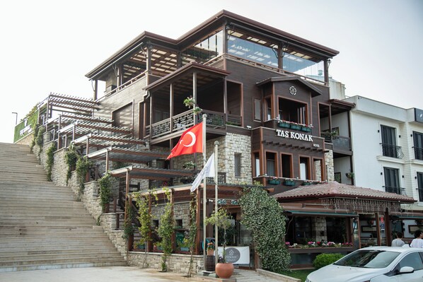 A hotel with a stone facade, multiple balconies, and a flag.