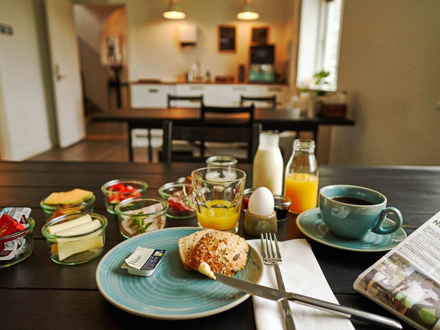 Una mesa de desayuno con diferentes alimentos, un periódico y una taza de café.
