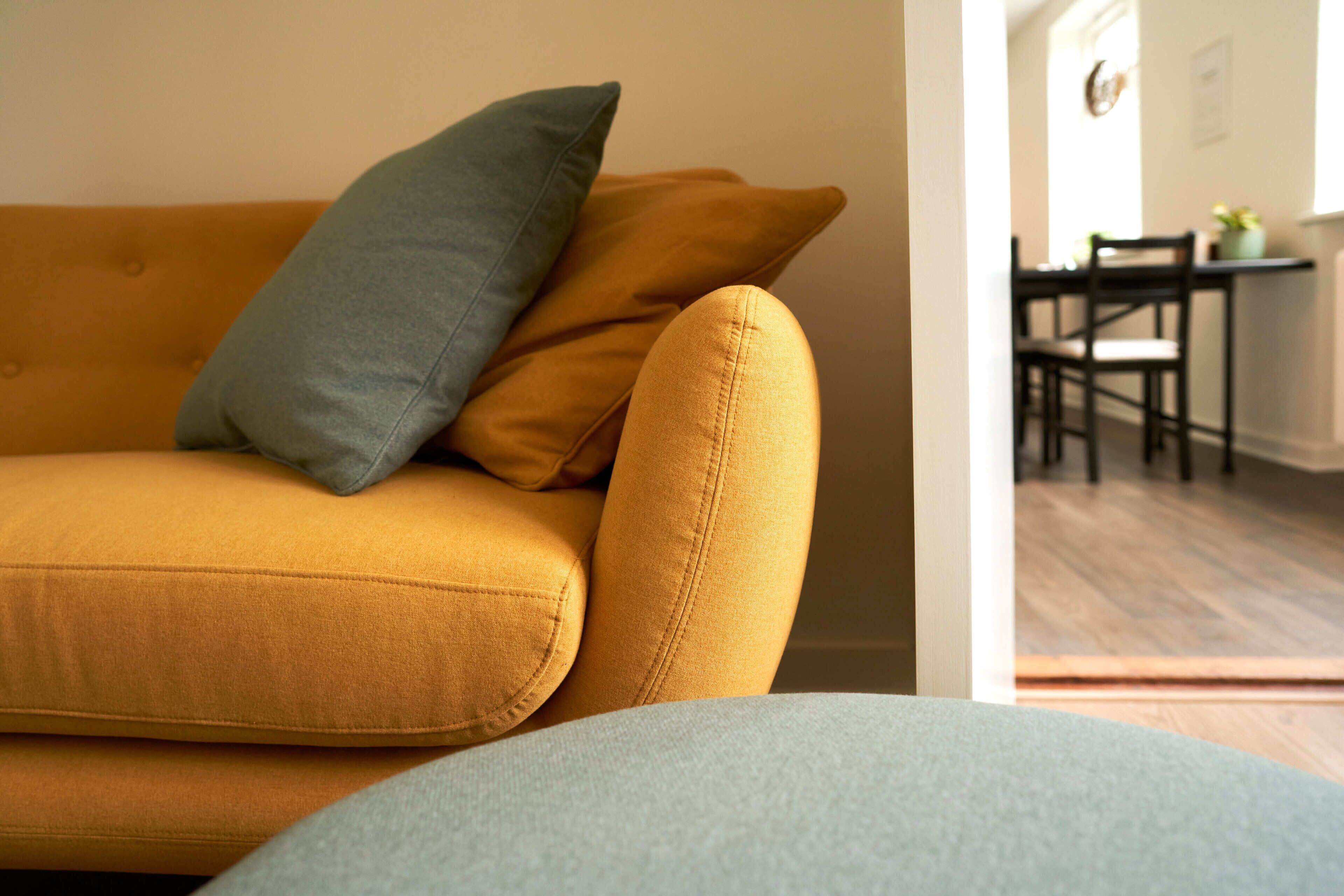 Ein gelbes Sofa mit einem grauen Kissen und einer hellgrauen Sitzkissen.