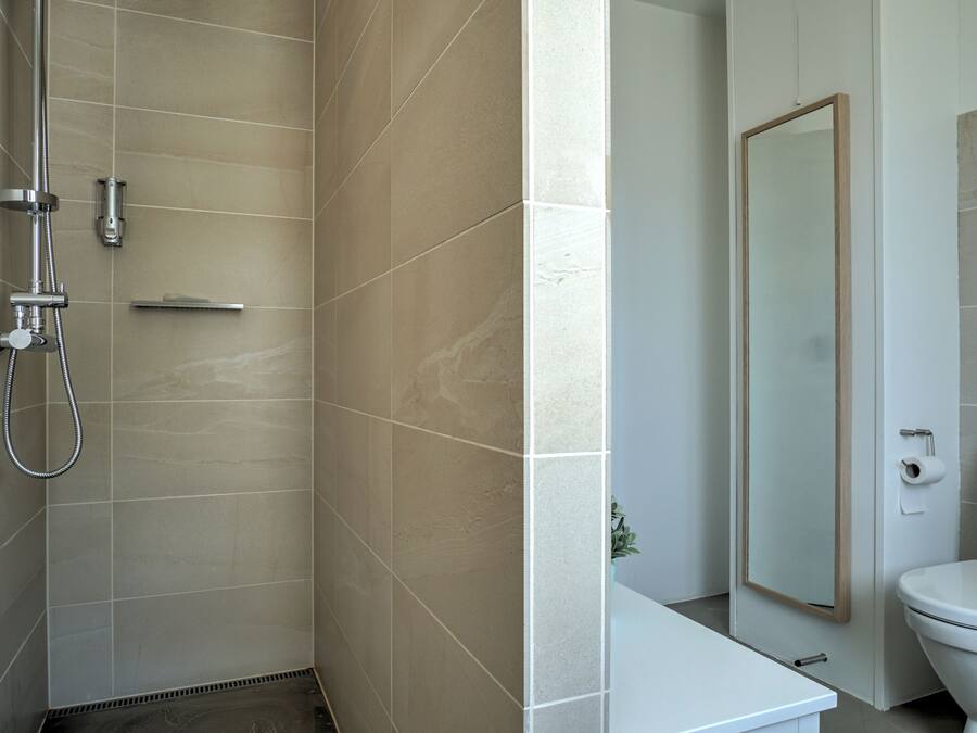 Une salle de bain moderne équipée d’une douche, de toilettes et d’un miroir.