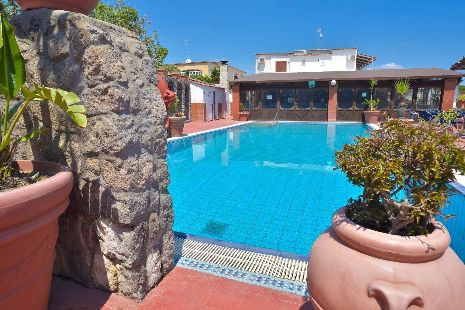 Una piscina con un muro de piedra y plantas en macetas.