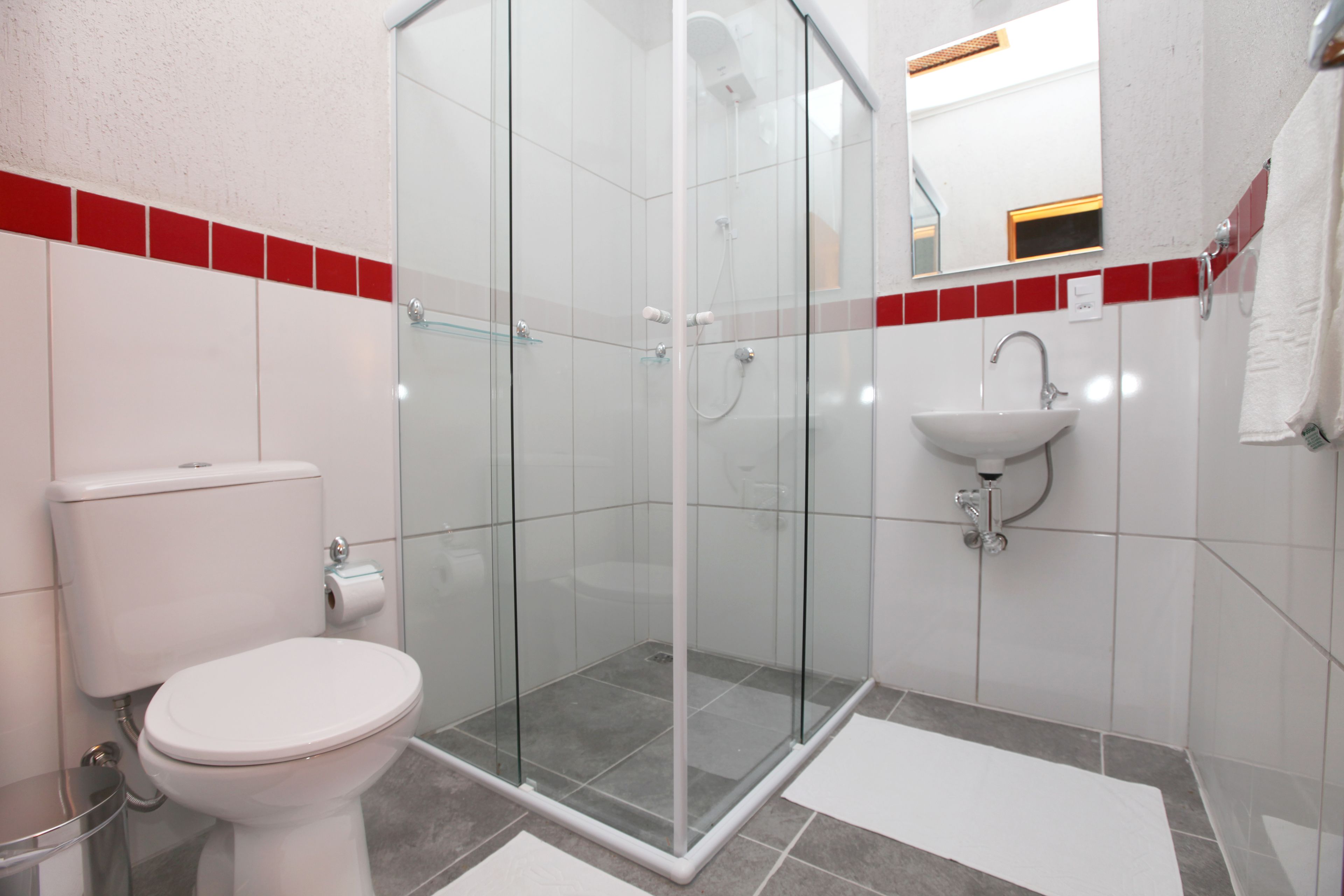 Un bagno moderno con doccia vetro, water bianco e lavabo.