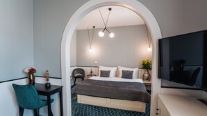 A modern hotel room with a bed, a desk, a TV, and a decorative vase. - Hotel Golfi (Podebrady)
