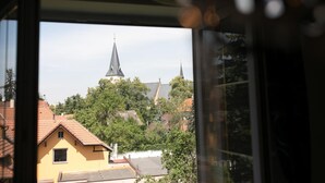 A view through a window of a building with a church steeple and surrounding residential buildings.