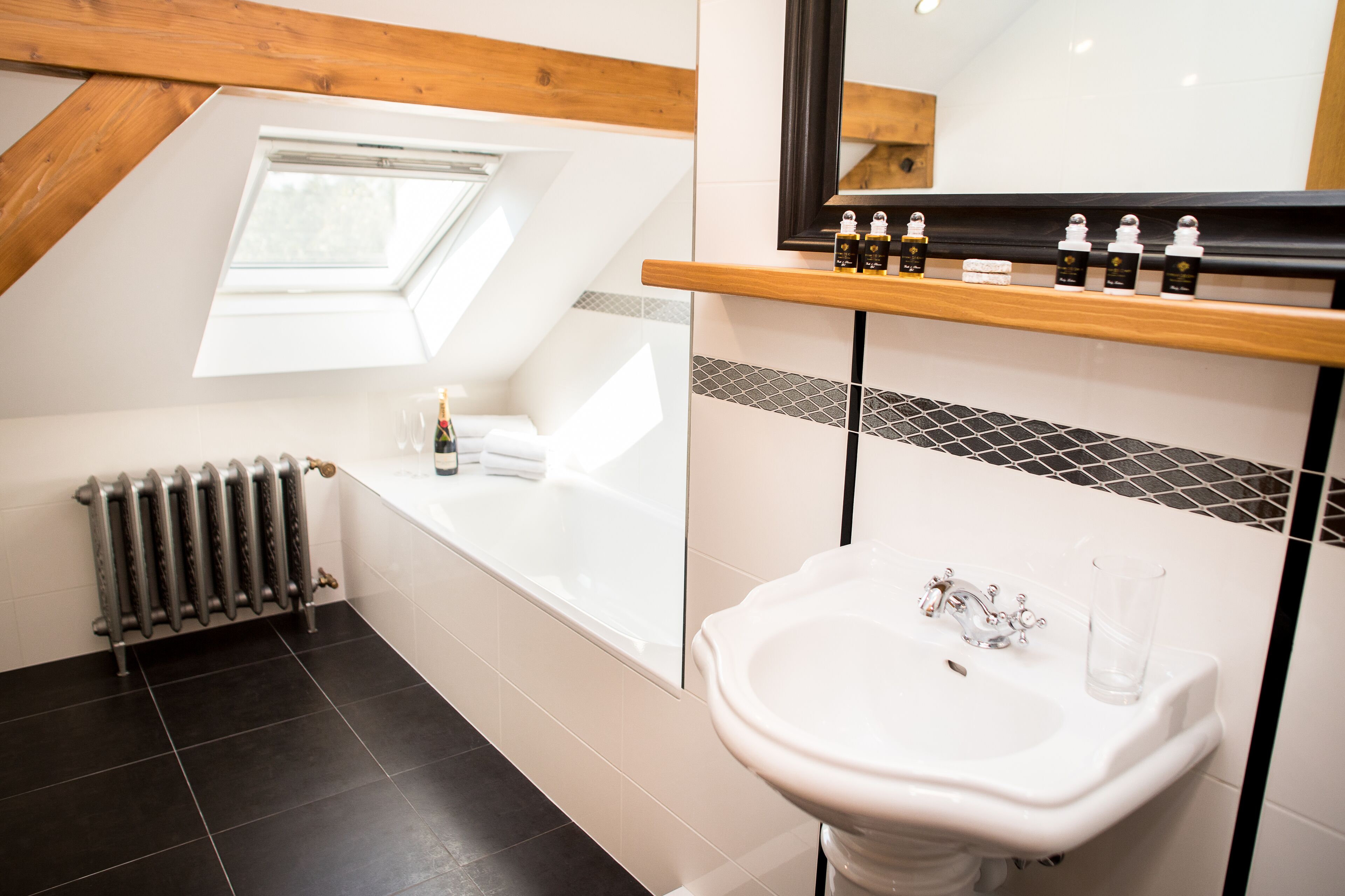 Ein modernes Badezimmer mit Dachfenster, einer Badewanne, einem weißen Waschbecken und einem Ablagefach für Toilettenartikel.