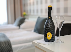 A bottle of BePIL NEO DOC EXCITING wine and a wine glass on a table in a hotel room.