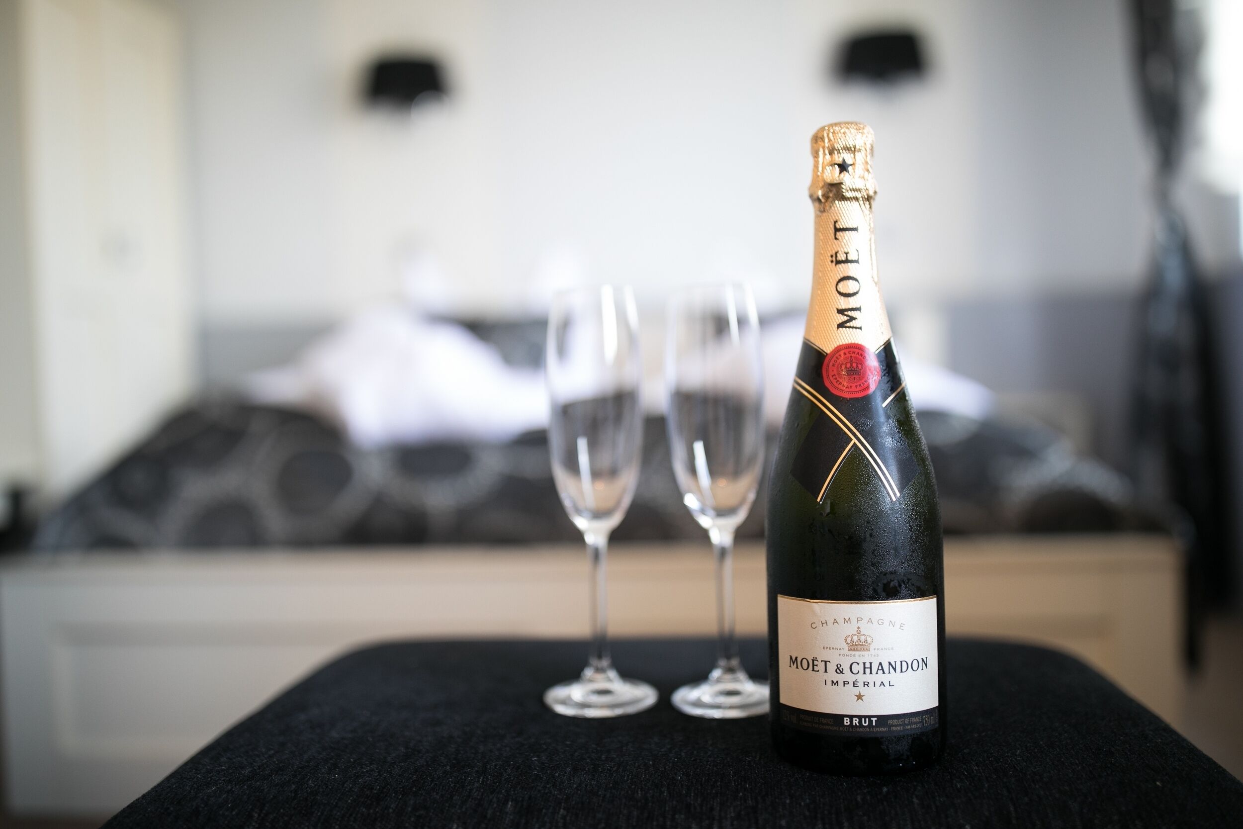 A bottle of Moët & Chandon Imperial Brut champagne on a black table with two empty glasses.