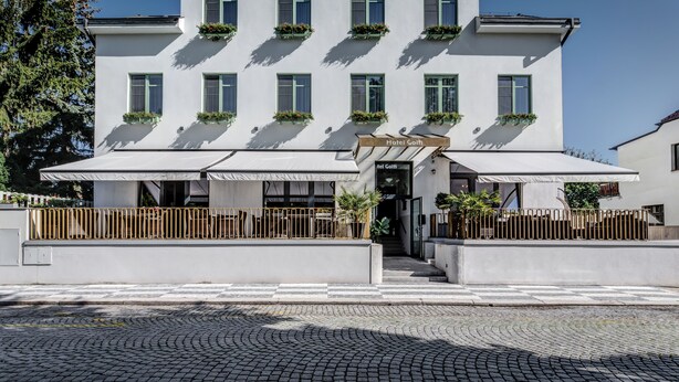 A modern hotel named "Hotel Golfi" with a white facade, multiple windows, and outdoor seating areas.