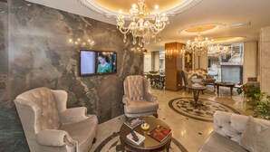 A luxurious lobby with marble walls, plush seating, a chandelier, and a television. - Viore Hotel (Istanbul)