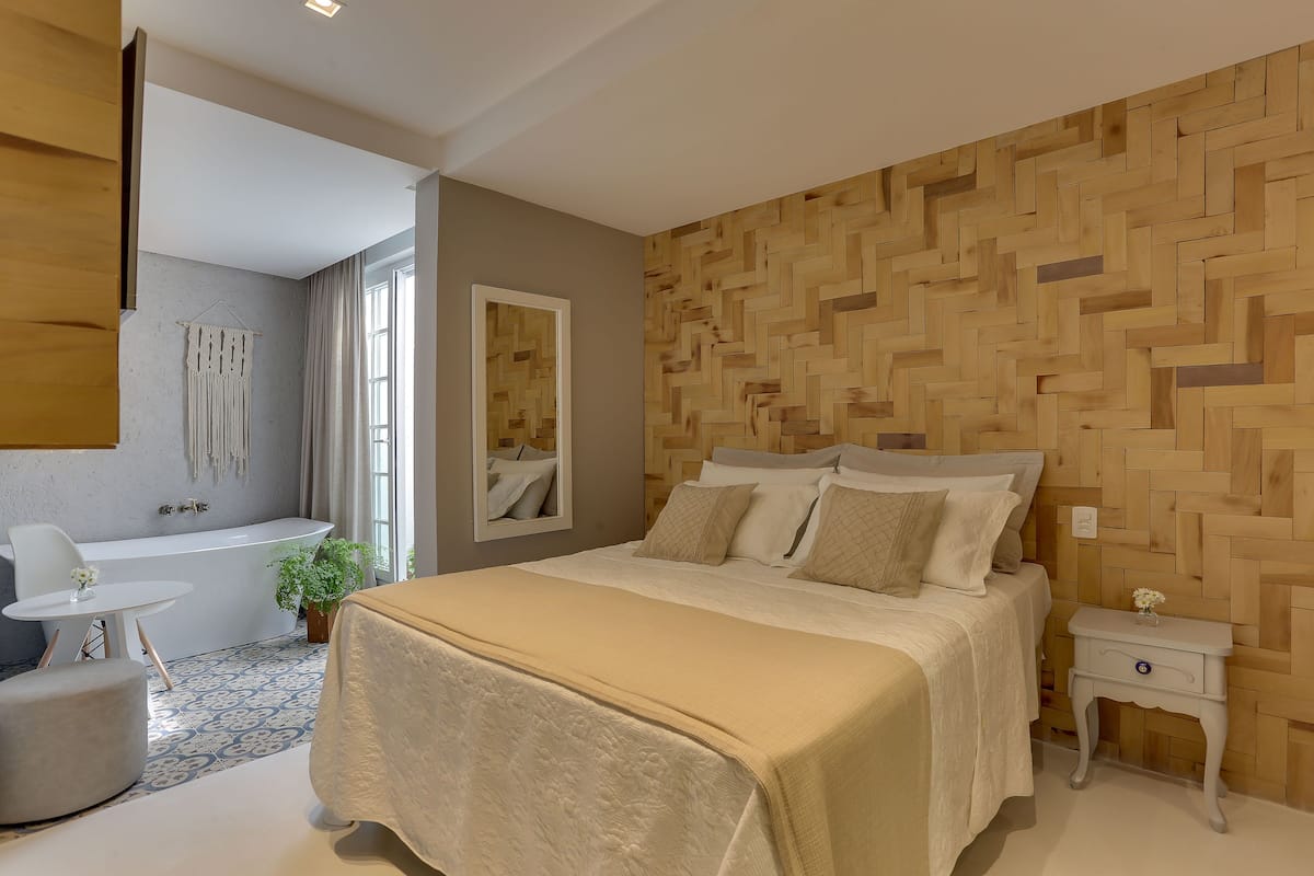 Une chambre moderne avec un grand lit, une baignoire intégrée et un panneau mural en bois.