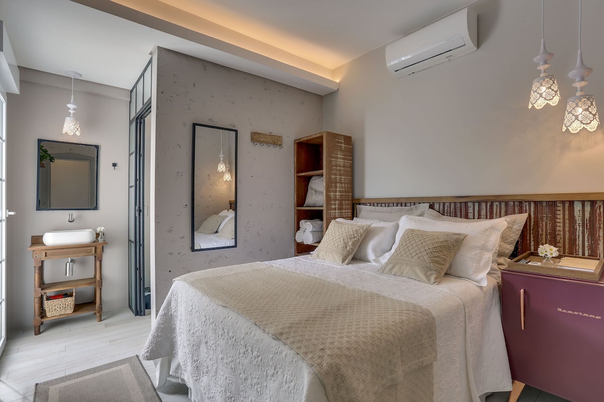 Une chambre à coucher comprenant un lit, une table de chevet, une armoire et un miroir.