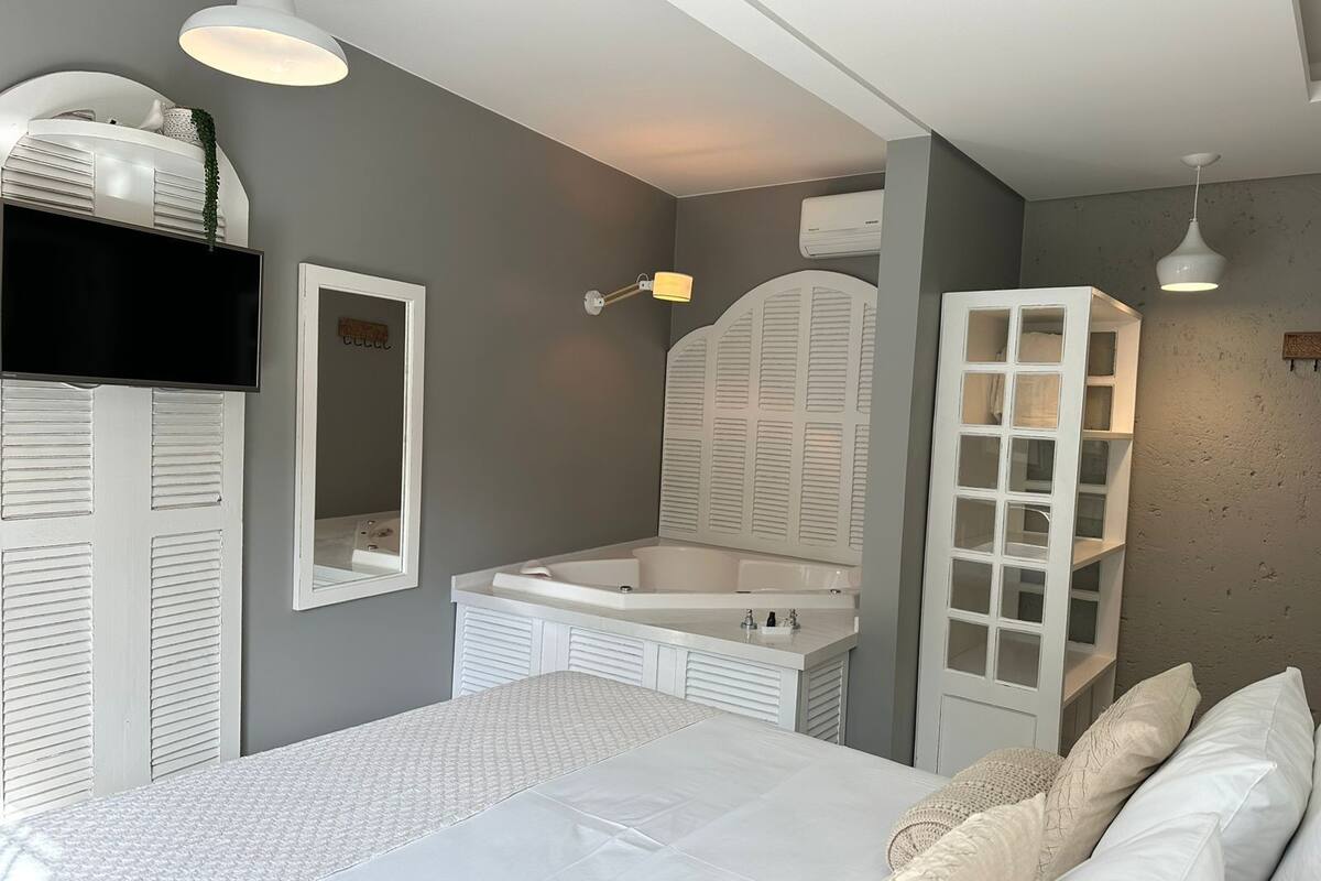 Une chambre à coucher comprenant un lit, une coiffeuse avec un miroir, une étagère intégrée et un luminaire au plafond.