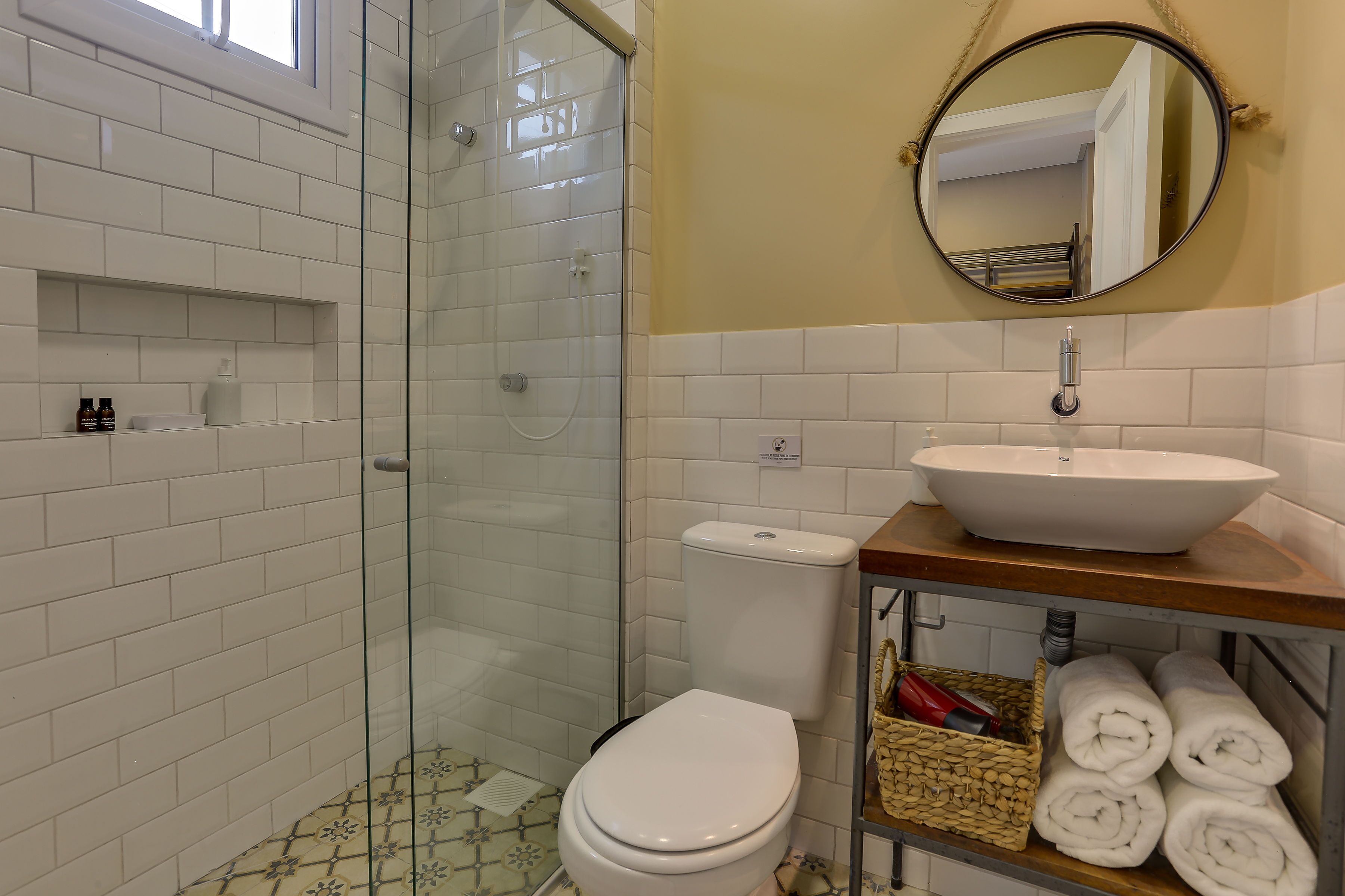 A bathroom with a glass shower enclosure, a white toilet, a sink with a vessel basin, and a mirror above the sink.