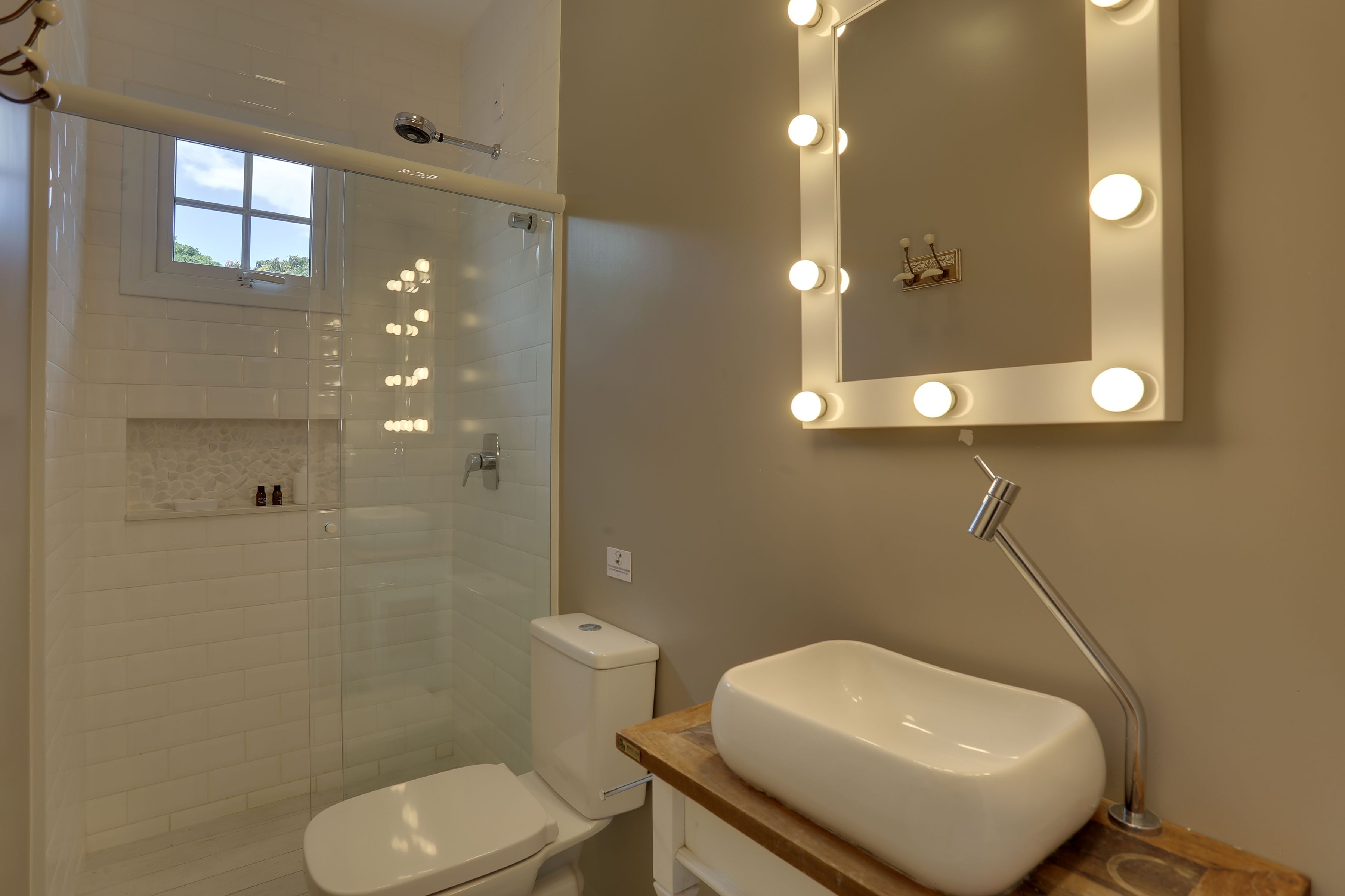 Une salle de bain avec une douche à parois de verre, des toilettes, un meuble-lavabo et un miroir avec éclairage.