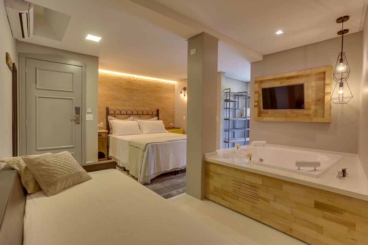 Une chambre moderne avec un grand lit, une tête de lit en bois et un téléviseur intégré.