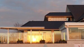 A modern house with a covered porch, large windows, and a brick facade. - Strand Hotel Dangast (Varel)