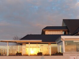 Ein modernes Haus mit einer überdachten Veranda, großen Fenstern und einer Ziegelaußenwand.