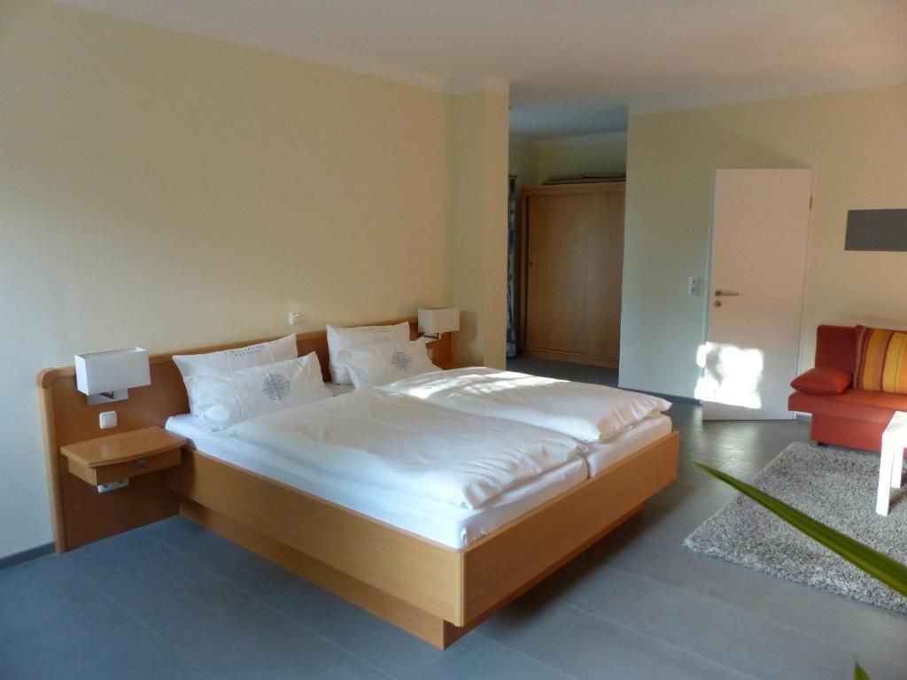 A modern bedroom with a large bed, bedside tables, a wardrobe, and a red sofa.